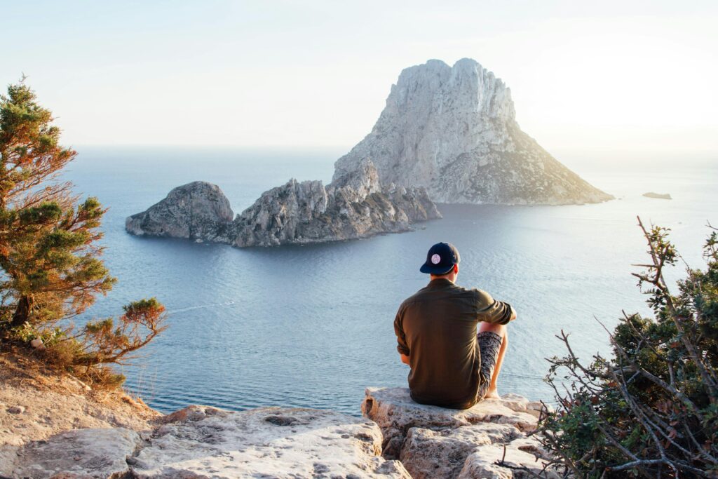 A man sitting on a rock looking at a body of water